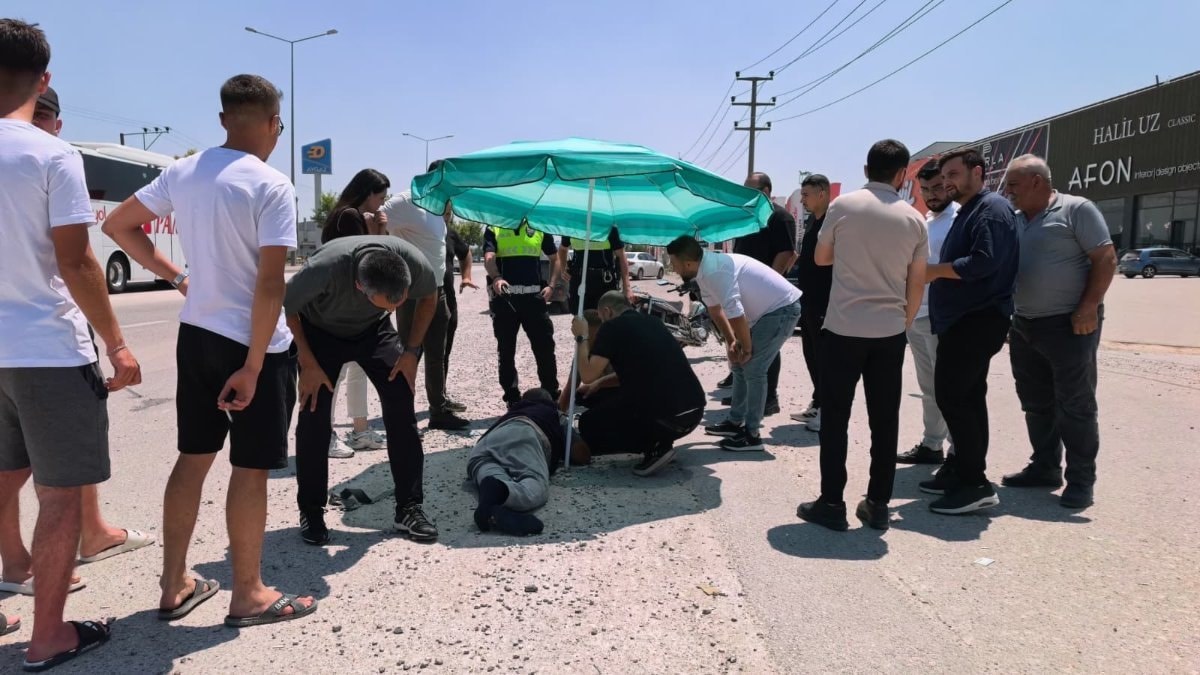 Bursa'da yerdeki yaralı sürücüyü güneşten korumak için plaj şemsiyesi açtılar
